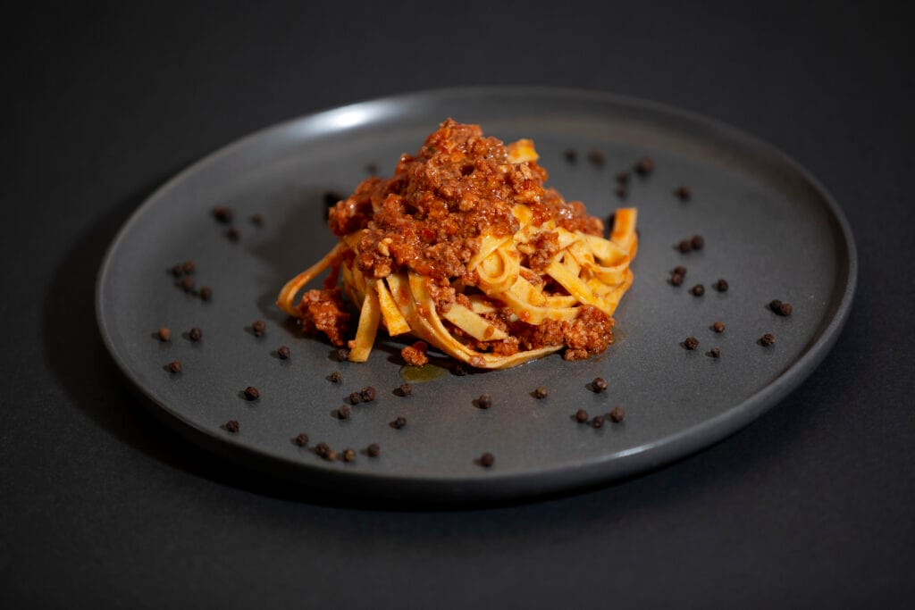 Tagliatelle with slow-cooked meat ragu on a dark plate