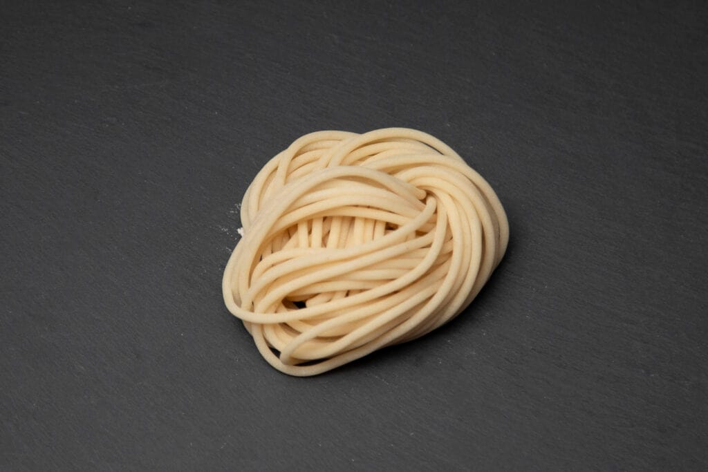 Nest of raw bucatini on dark slate