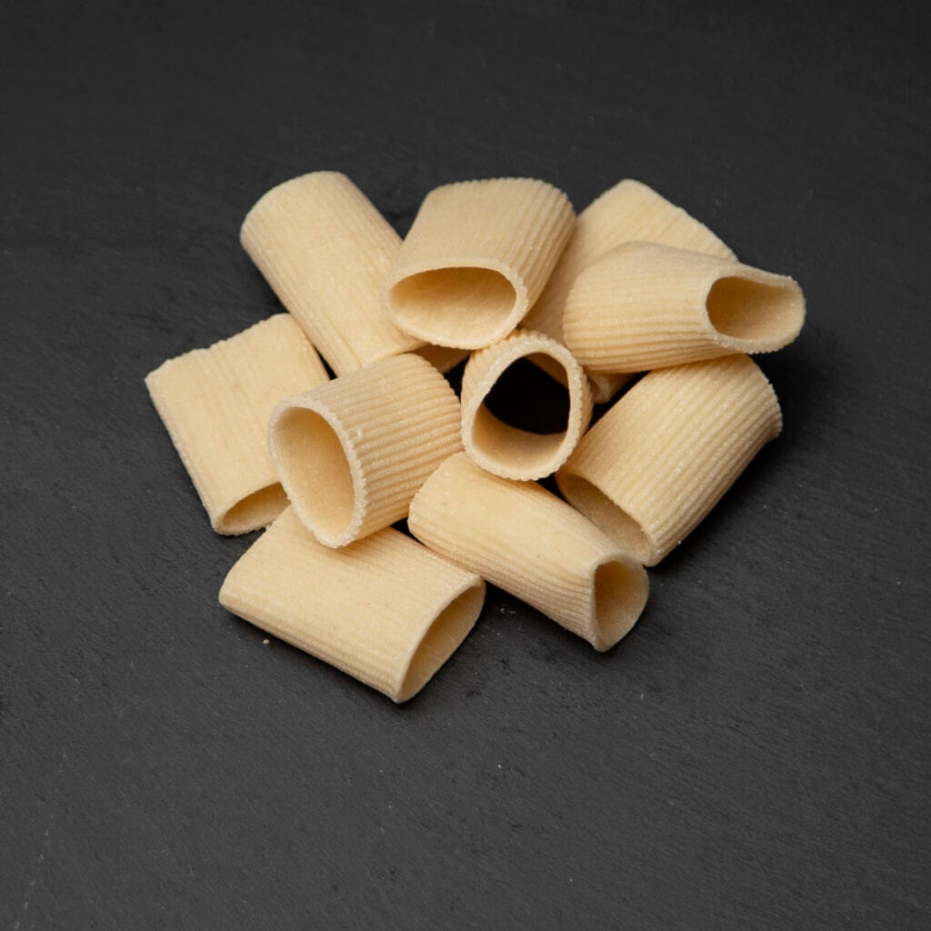 Raw paccheri tubes on dark slate